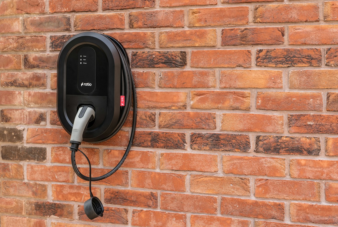 Borne de recharge connectée noire fixée sur un mur en briques