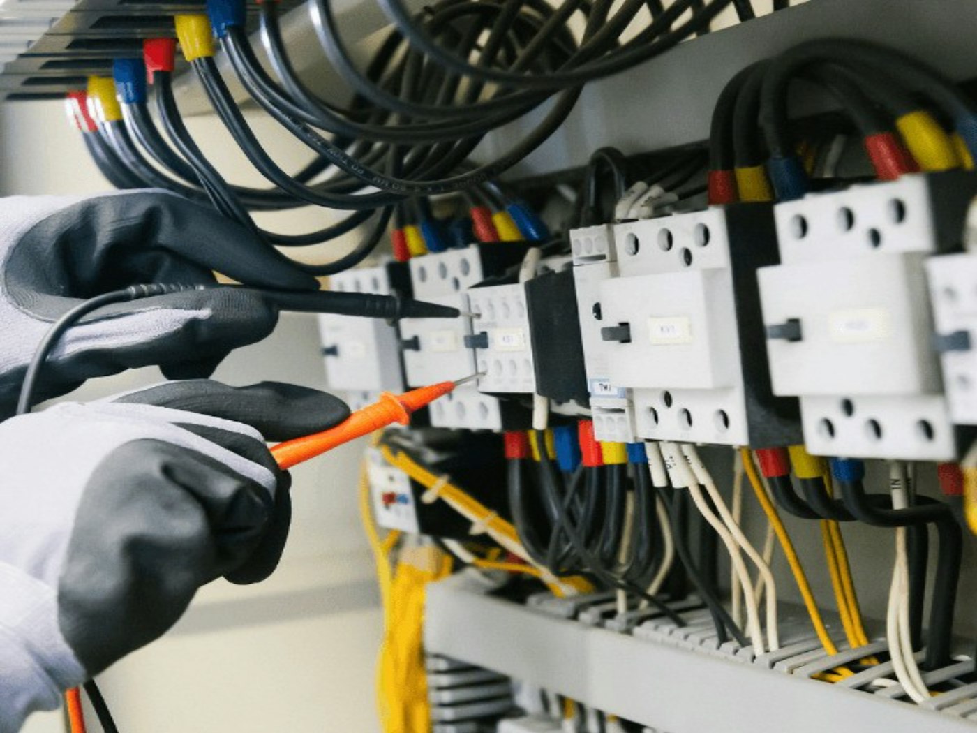 Électricien testant un tableau électrique industriel au multimètre